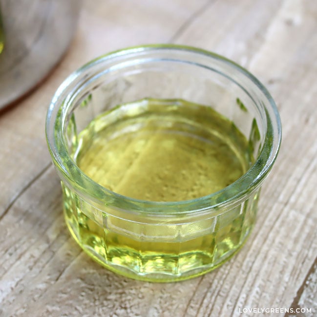 A yellow liquid half-fills a clear glass ramekin.