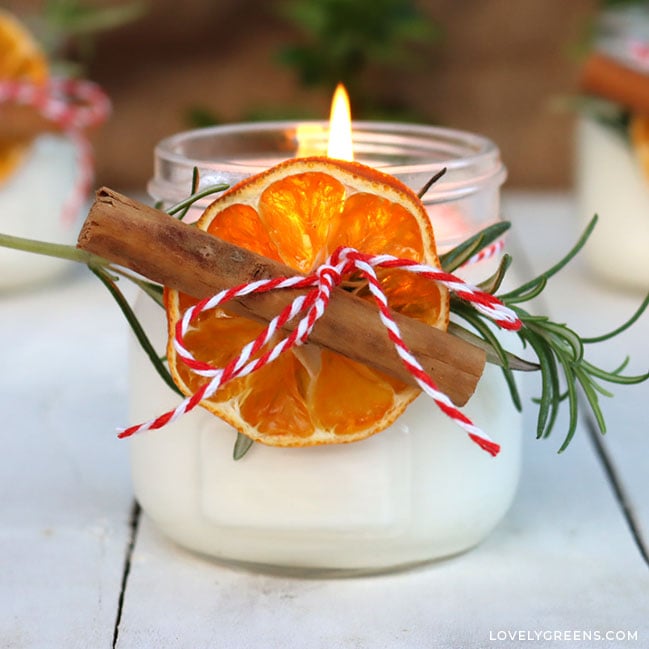 Close-up of one of the candles lit. Light shines through the dried orange slice fixed to the front.