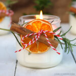 The front view of the finished Mason jar candles. One is lit in the foreground with the other two behind.