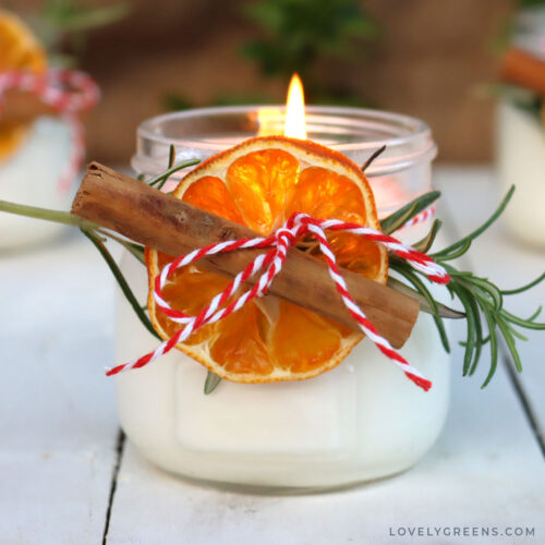 The front view of the finished Mason jar candles. One is lit in the foreground with the other two behind.