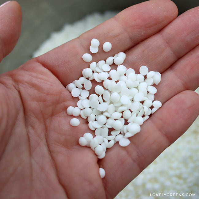 Close-up of a hand holding white wax pellets.