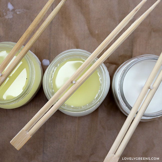 Looking down at container candles with wicks held secure and centered with chopsticks.