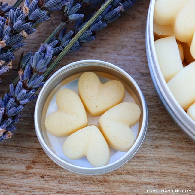 Four heart-shaped lotion dots sit inside a metal lip balm tin.