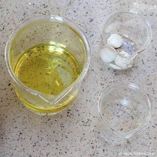 Three glass containers hold small amounts of yellow avocado oil, clear lavender essential oil, and three tiny scoops of very fine oatmeal powder.