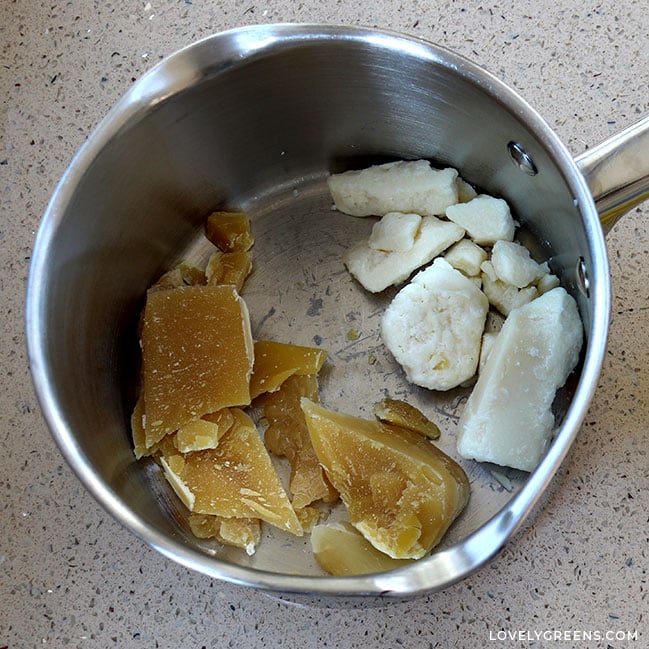 Shards of yellow beeswax and chunks of white shea butter in a stainless steel sauce pan.