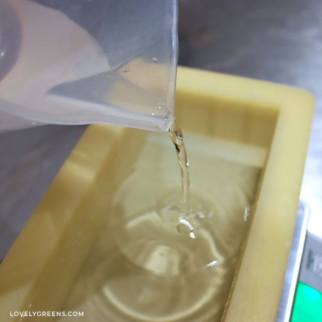 A clear jug pours water into a rectangular mold sitting on a digital scale.